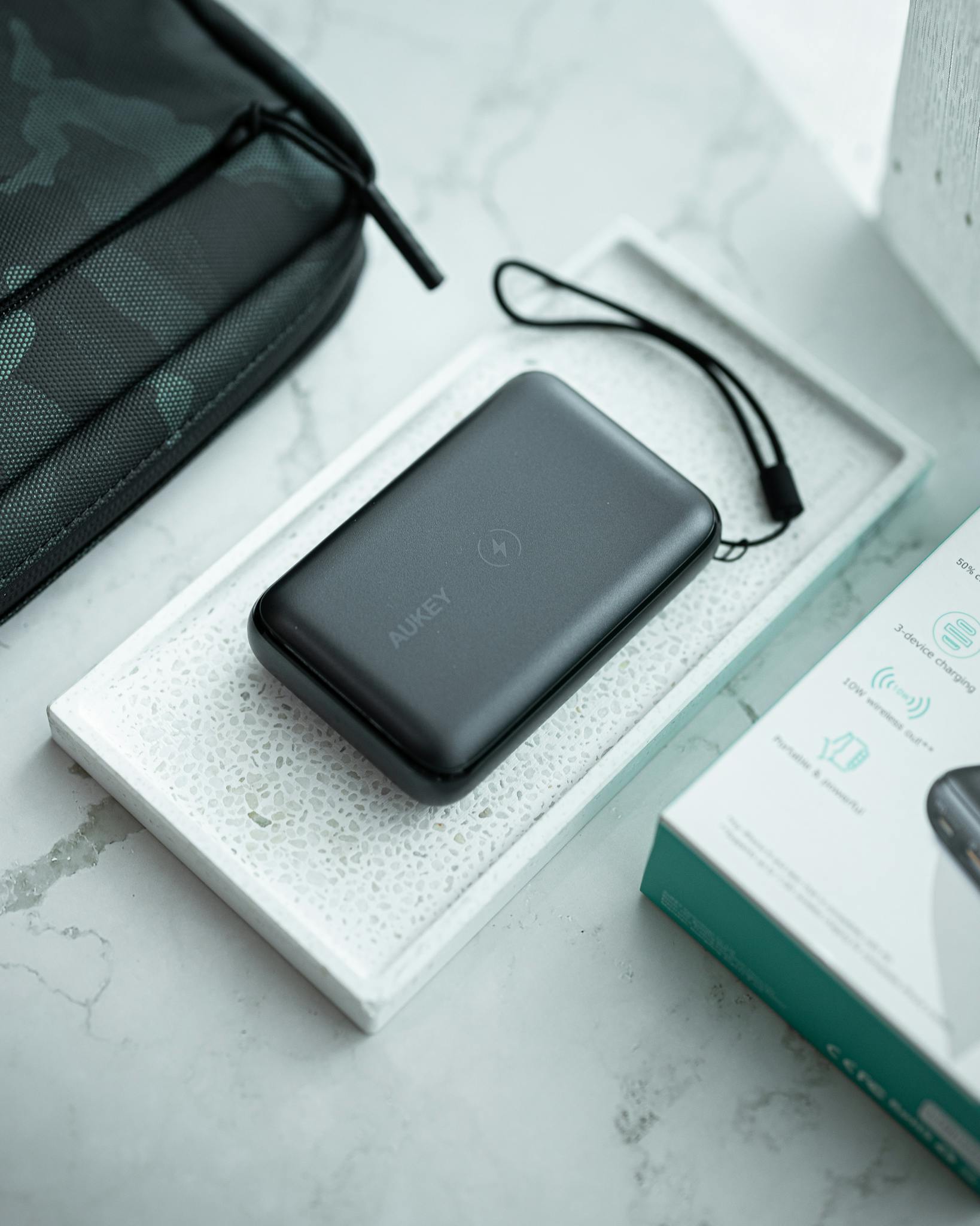 A sleek Aukey power bank placed on a marble surface beside its packaging, showcasing modern design.