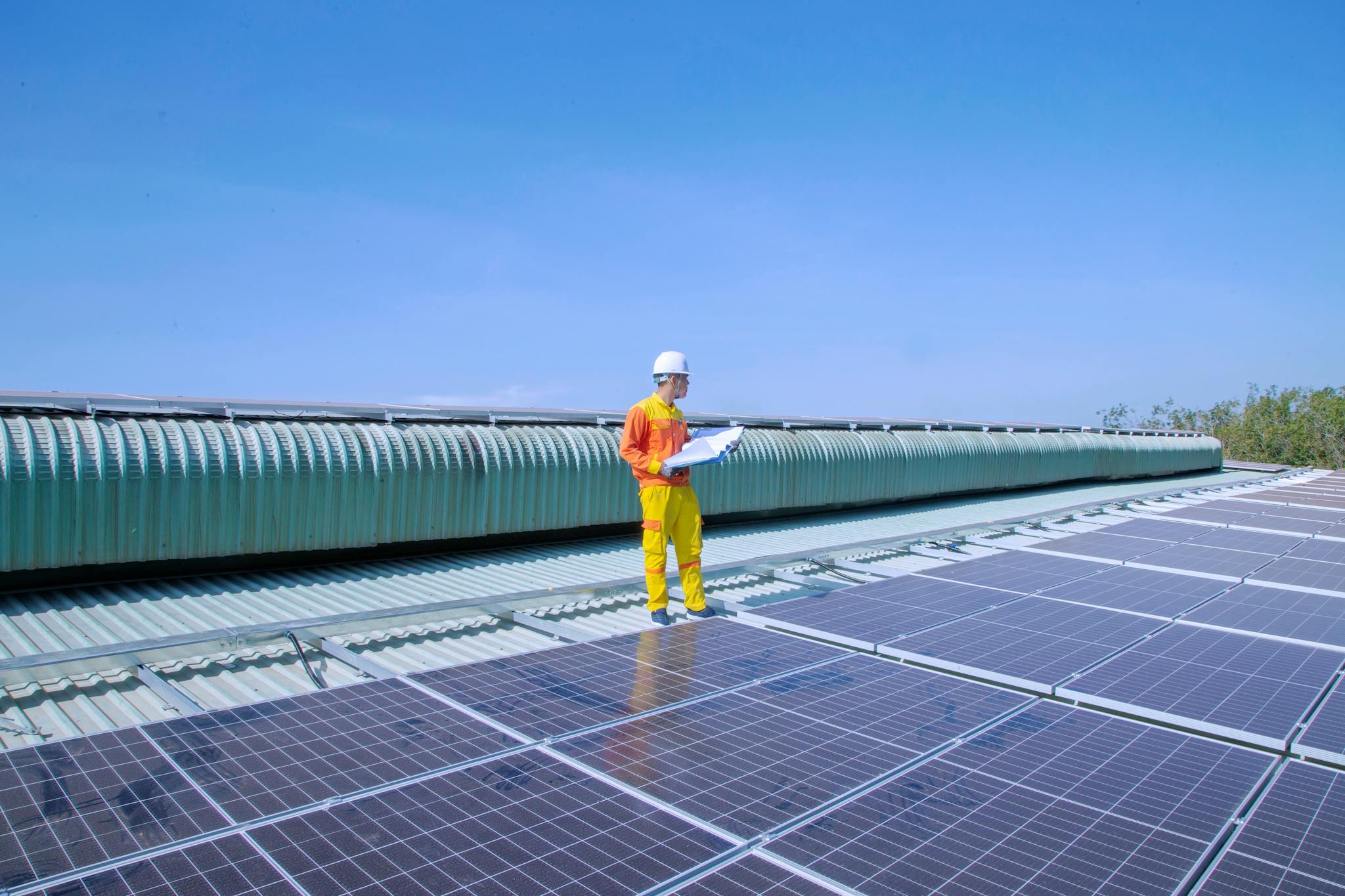 Technician examining solar panels on a rooftop, emphasizing renewable energy.